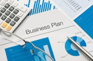 A business plan is shown on top of some papers.