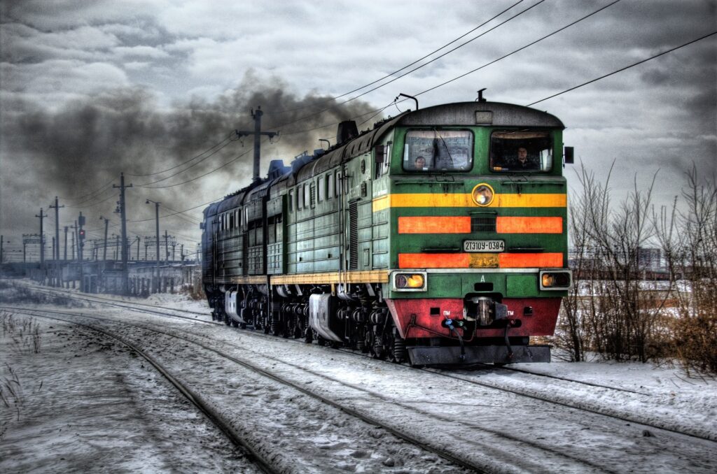 A train is traveling down the tracks in winter.