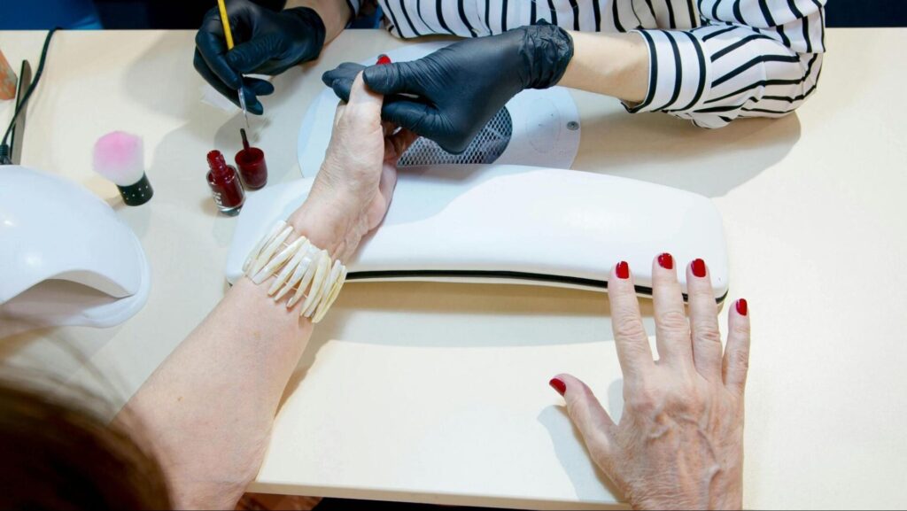 Woman getting red nail polish manicure.